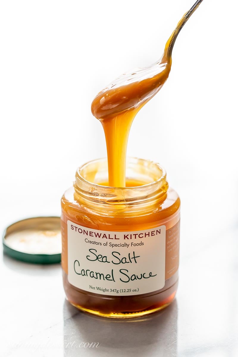 A jar of sea salt caramel sauce with a spoon drizzling caramel