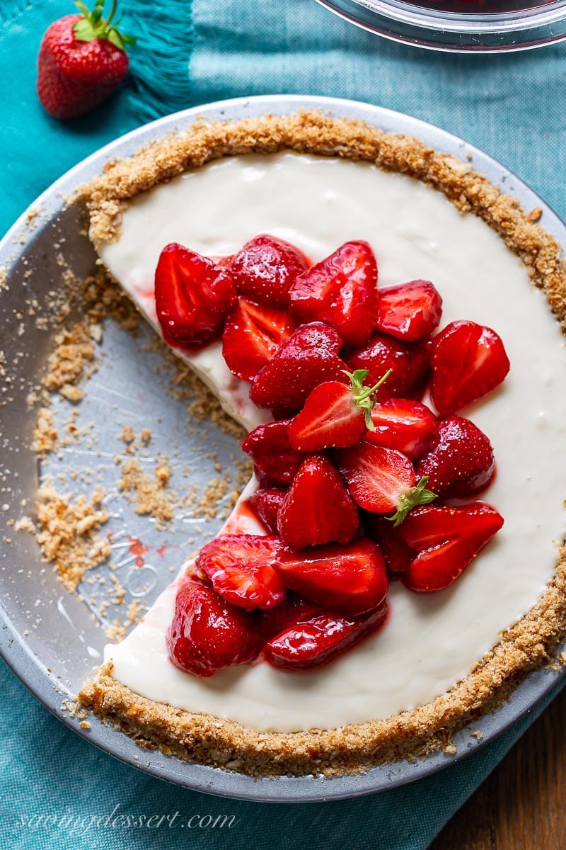 An overhead view of a sliced strawberry cream cheese pie with strawberries on top