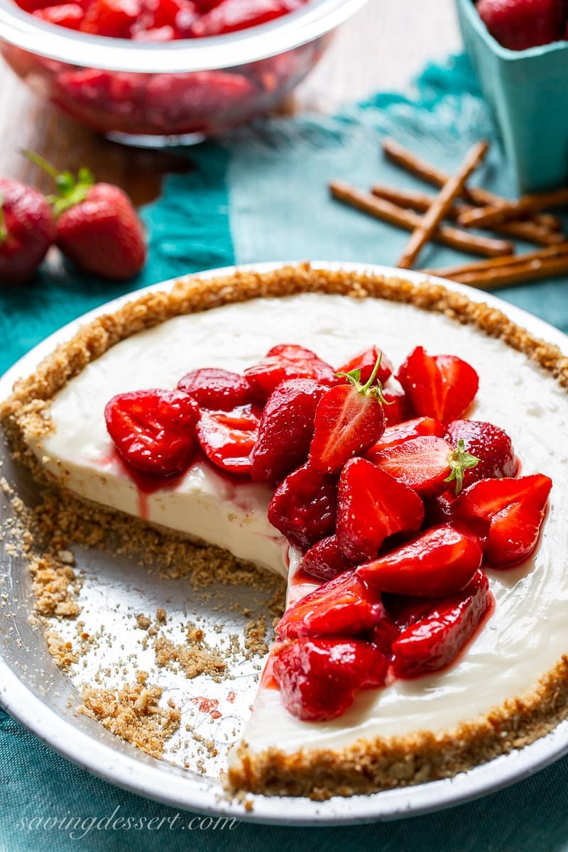 A sliced cream cheese pie topped with ripe, sliced strawberries