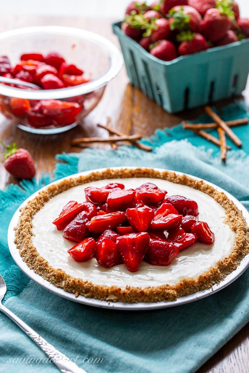 A cream cheese pie with pretzel crust topped with sliced strawberries 