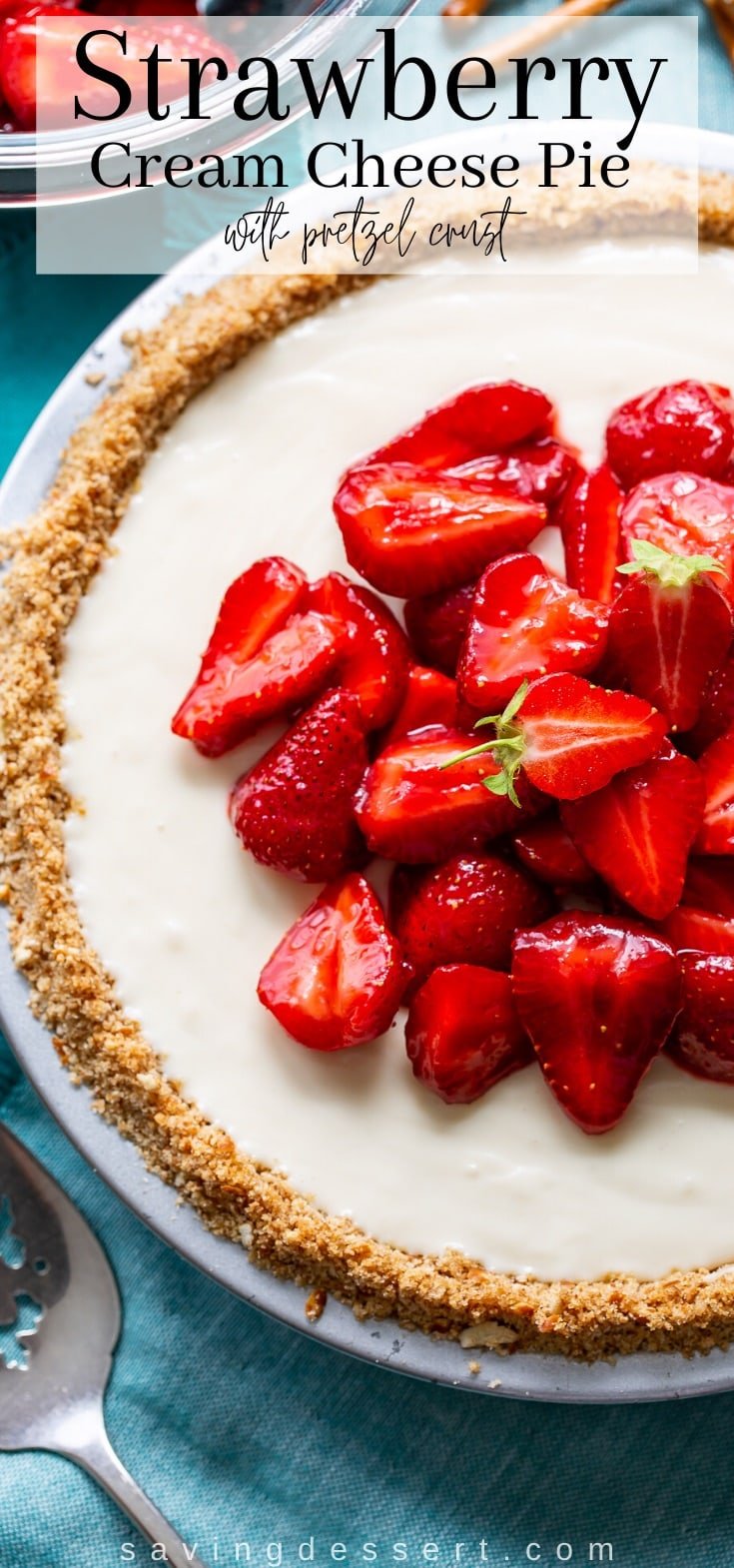 An overhead view of a whole cream cheese pie with pretzel crust, topped with red, ripe strawberries
