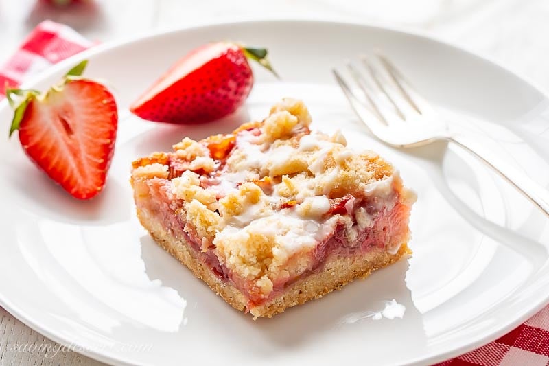 A square fruit bar with a crumble top served with sliced strawberries