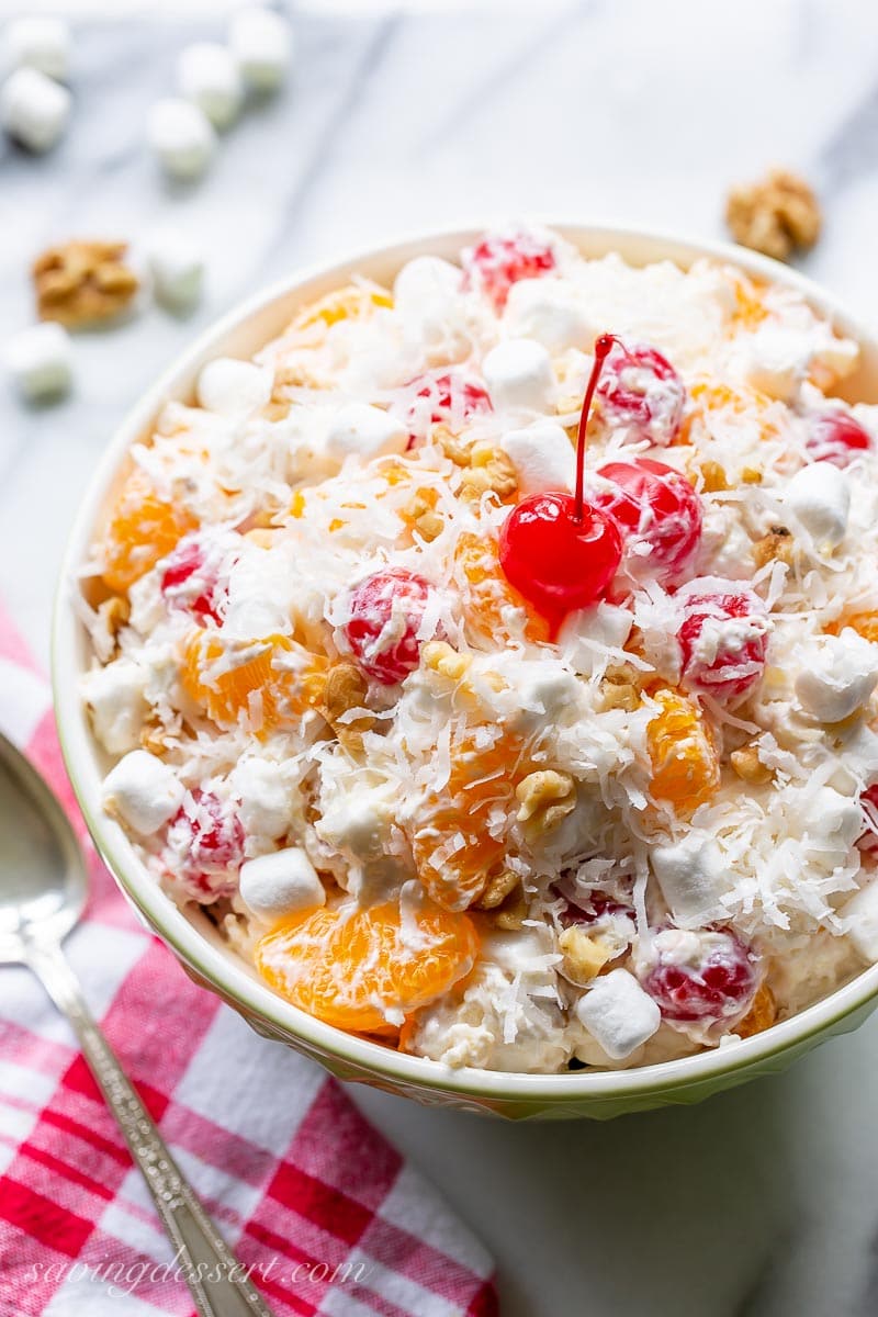 An overhead view of a bowl of fruit salad topped with a cherry and shredded coconut