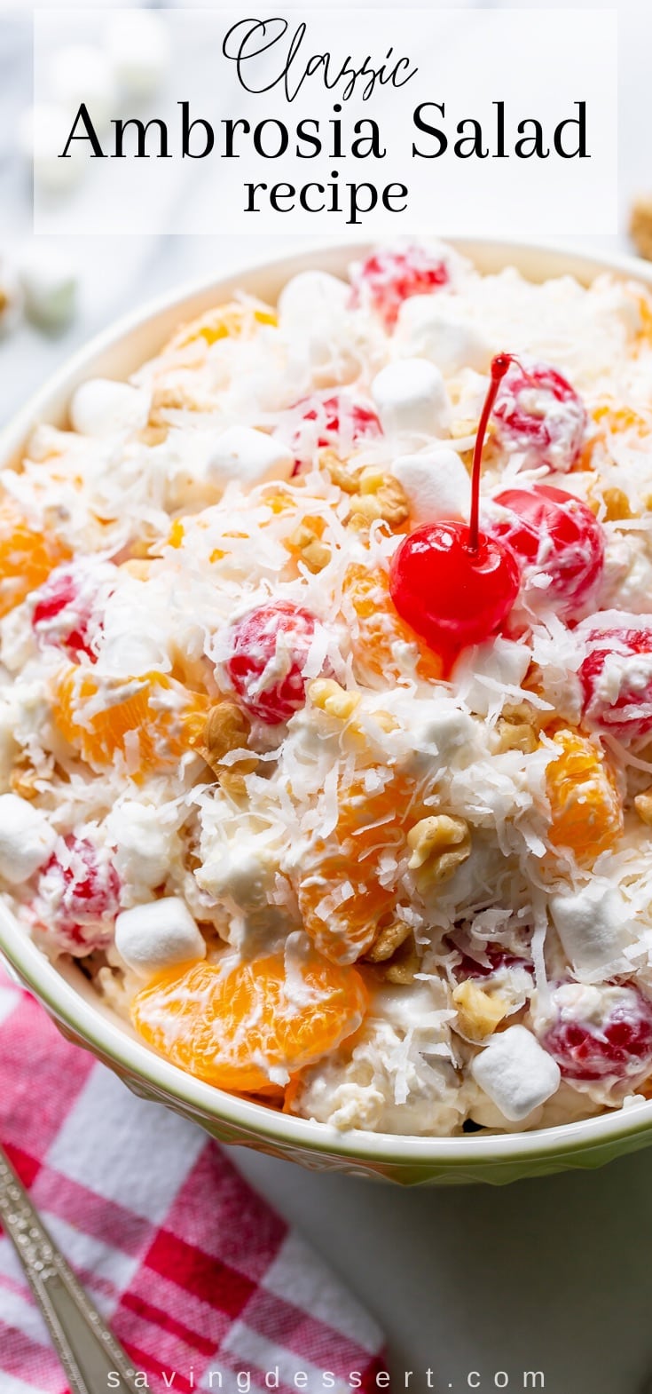 An overhead view of a big bowl of fruit salad with cherries, mandarin oranges, chopped walnuts, marshmallows and coconut.