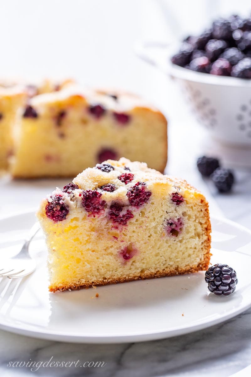 A slice of blackberry breakfast cake on a plate with fresh blackberries 