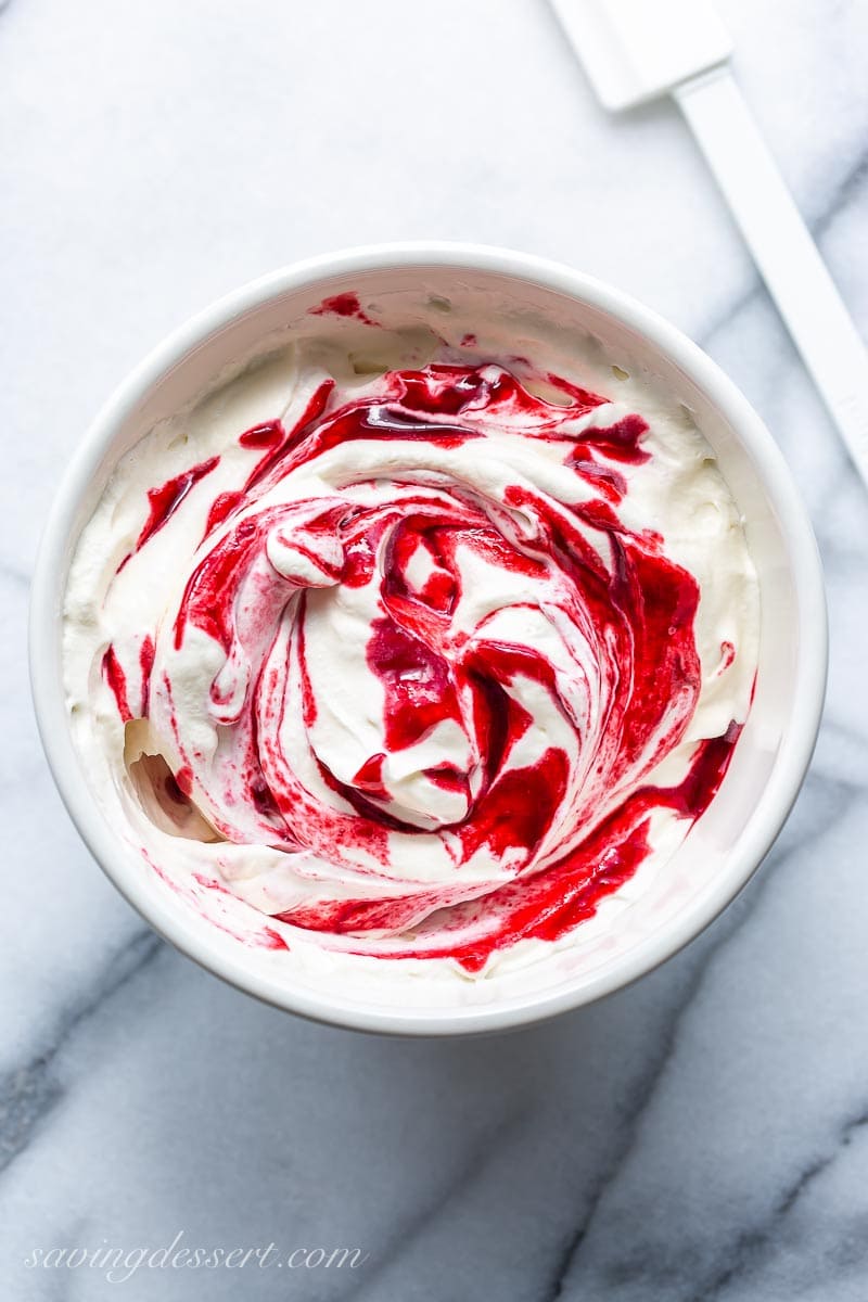 A bowl of whipped cream with blackberry puree swirled throughout