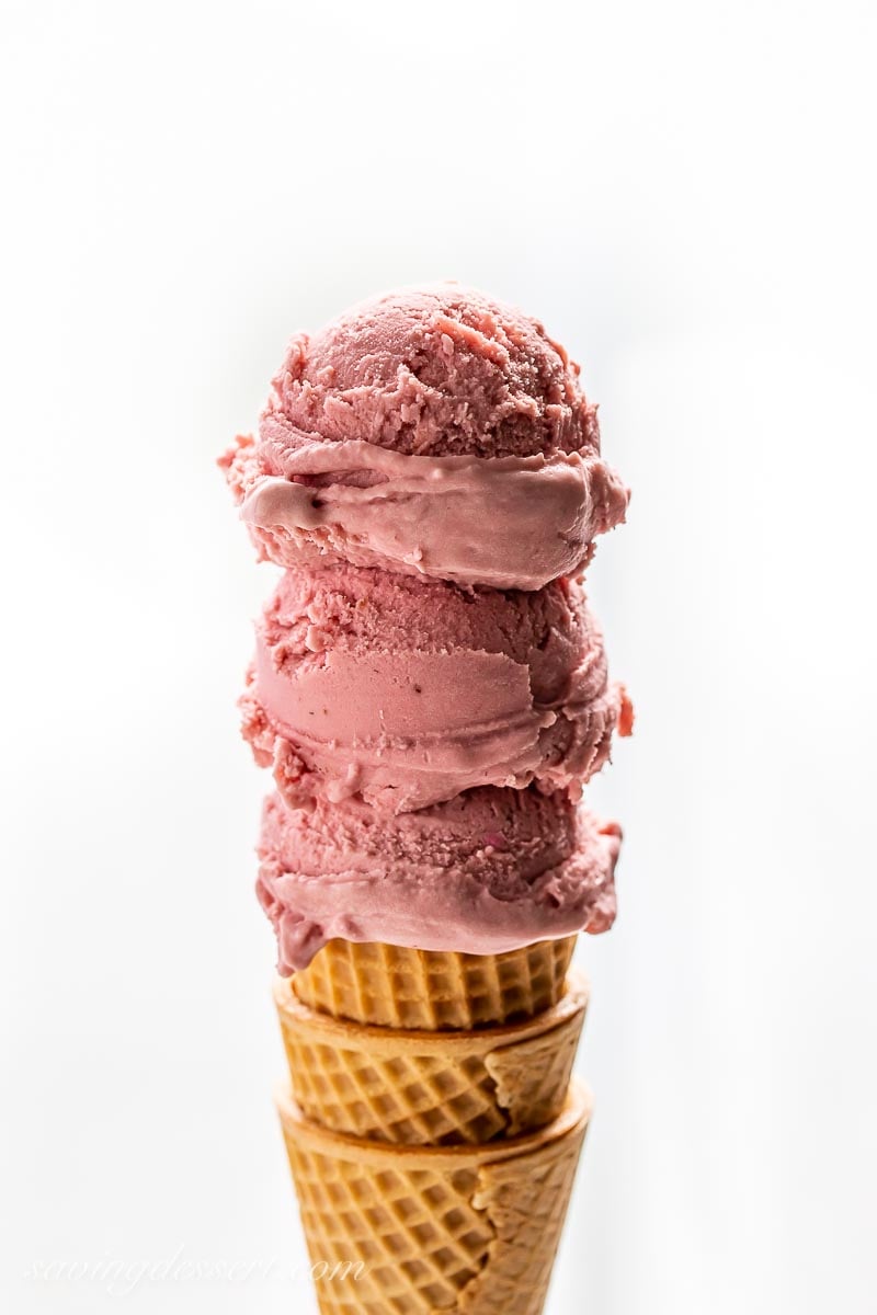 Three scoops of dark pinkish purple ice cream on a cone