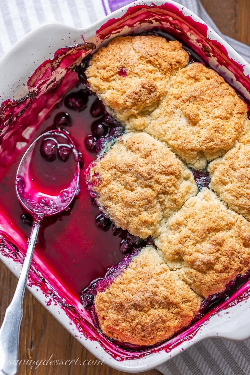 A casserole dish with a soupy fruit dessert with a biscuit topping