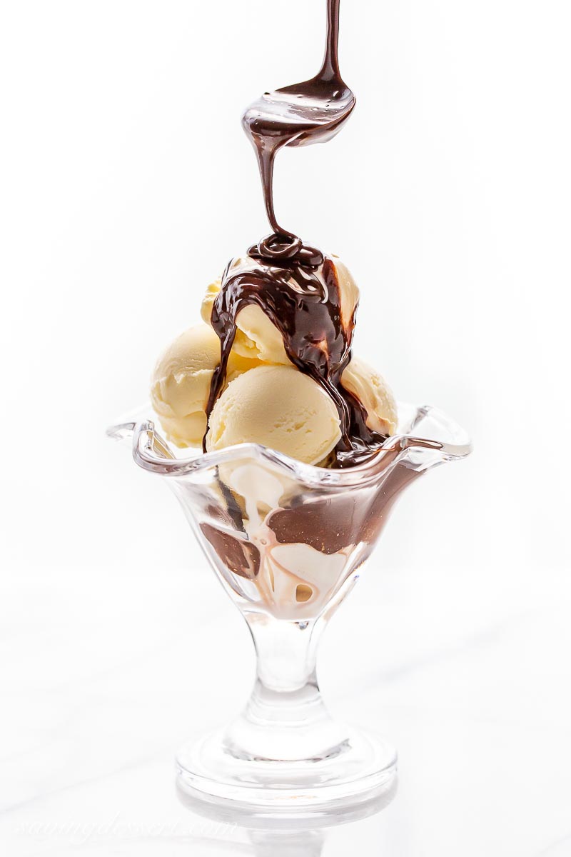 Scoops of ice cream being drizzled with hot fudge sauce