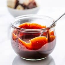 A wide mouth jar with chocolate sauce and a spoon
