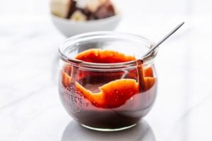 A wide mouth jar with chocolate sauce and a spoon
