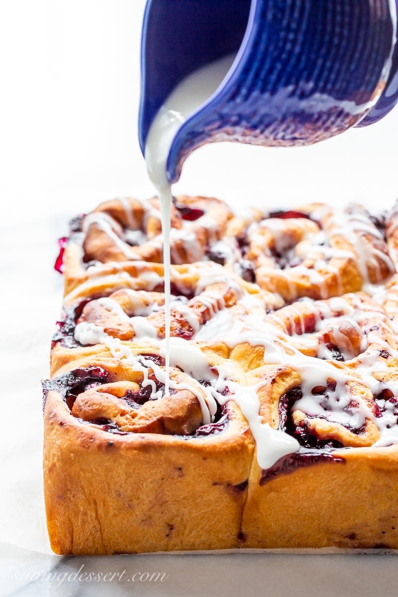 A side show of blueberry sweet rolls being drizzled with icing