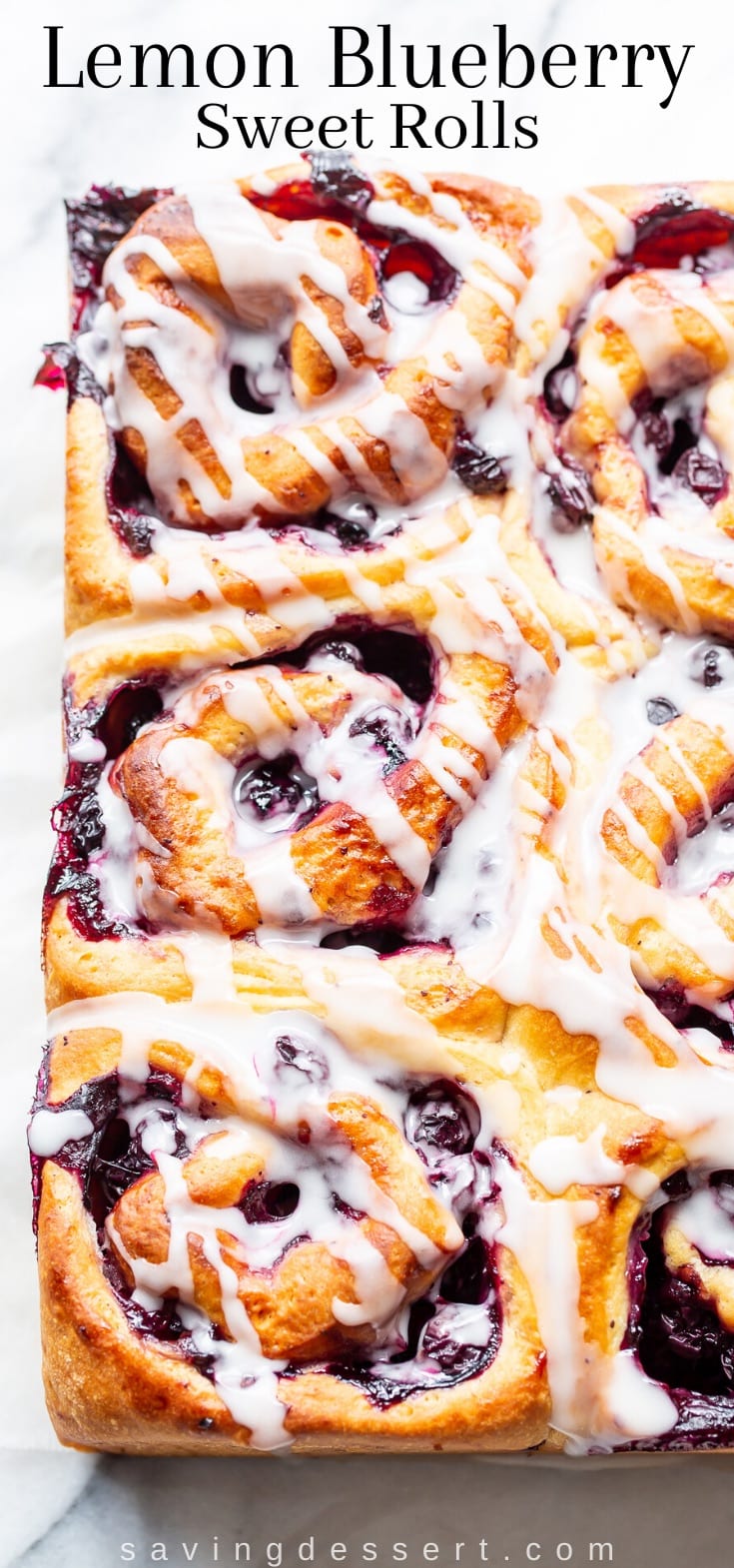 An overhead view of baked sweet rolls with blueberries and a simple drizzled glaze