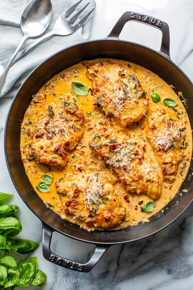 A skillet with chicken cutlets in a sun-dried tomato cream sauce