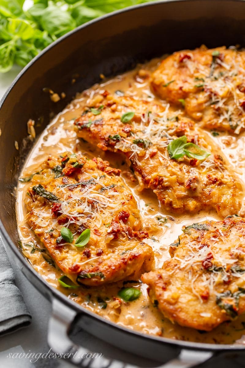 A skillet with sun-dried tomato cream sauce over chicken cutlets