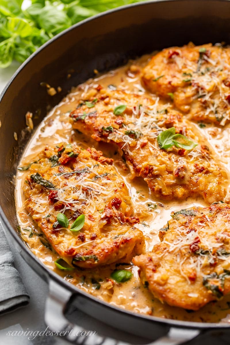 A skillet with sun-dried tomato cream sauce over chicken cutlets