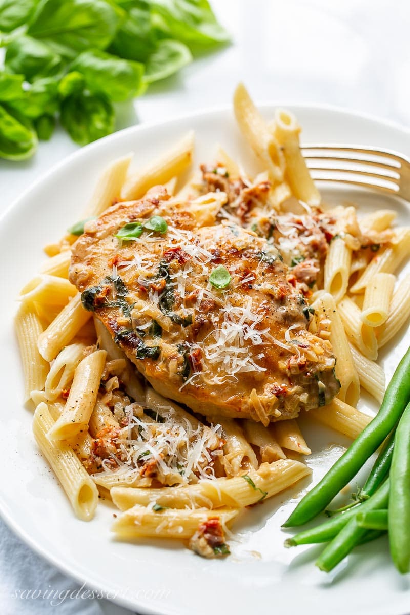 A plate with penne pasta and a chicken breast on top