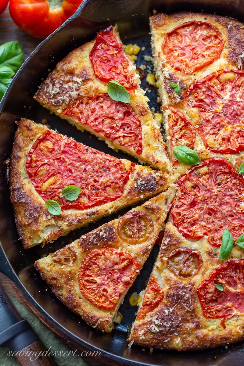 Sliced cornbread topped with tomatoes and basil leaves