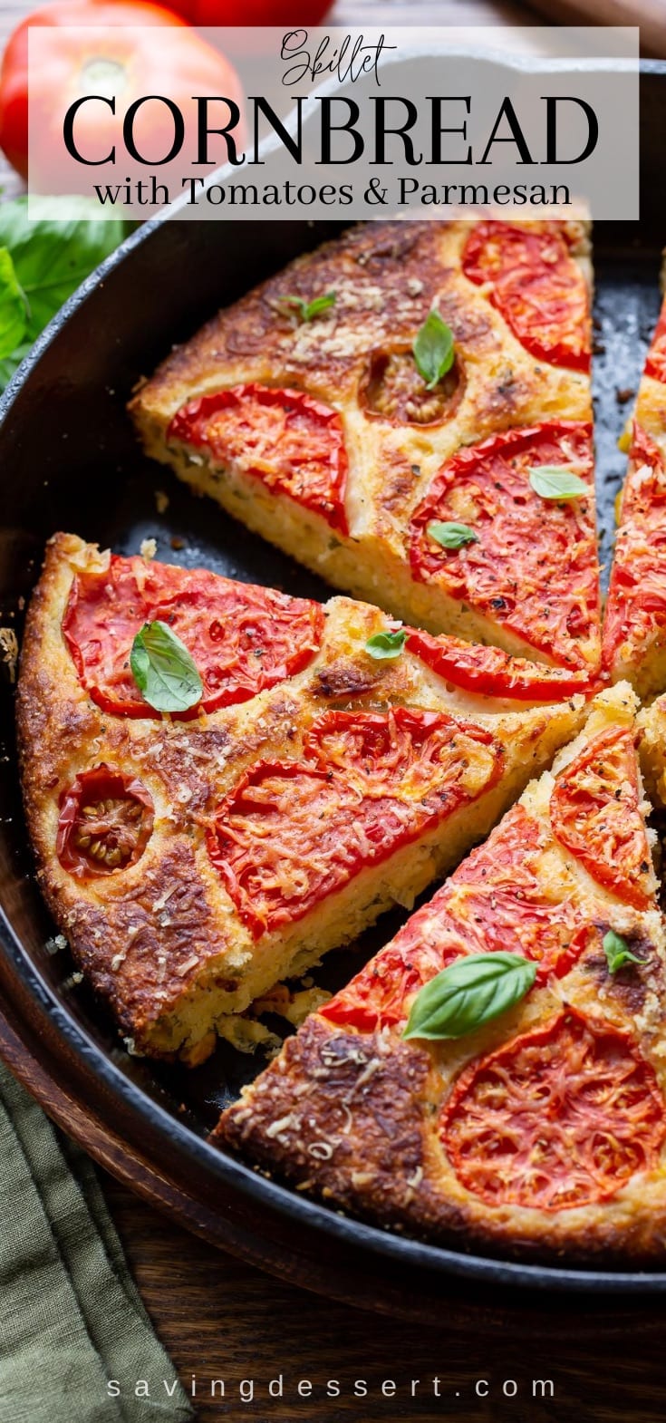 A cast iron skillet with cornbread topped with tomatoes and basil