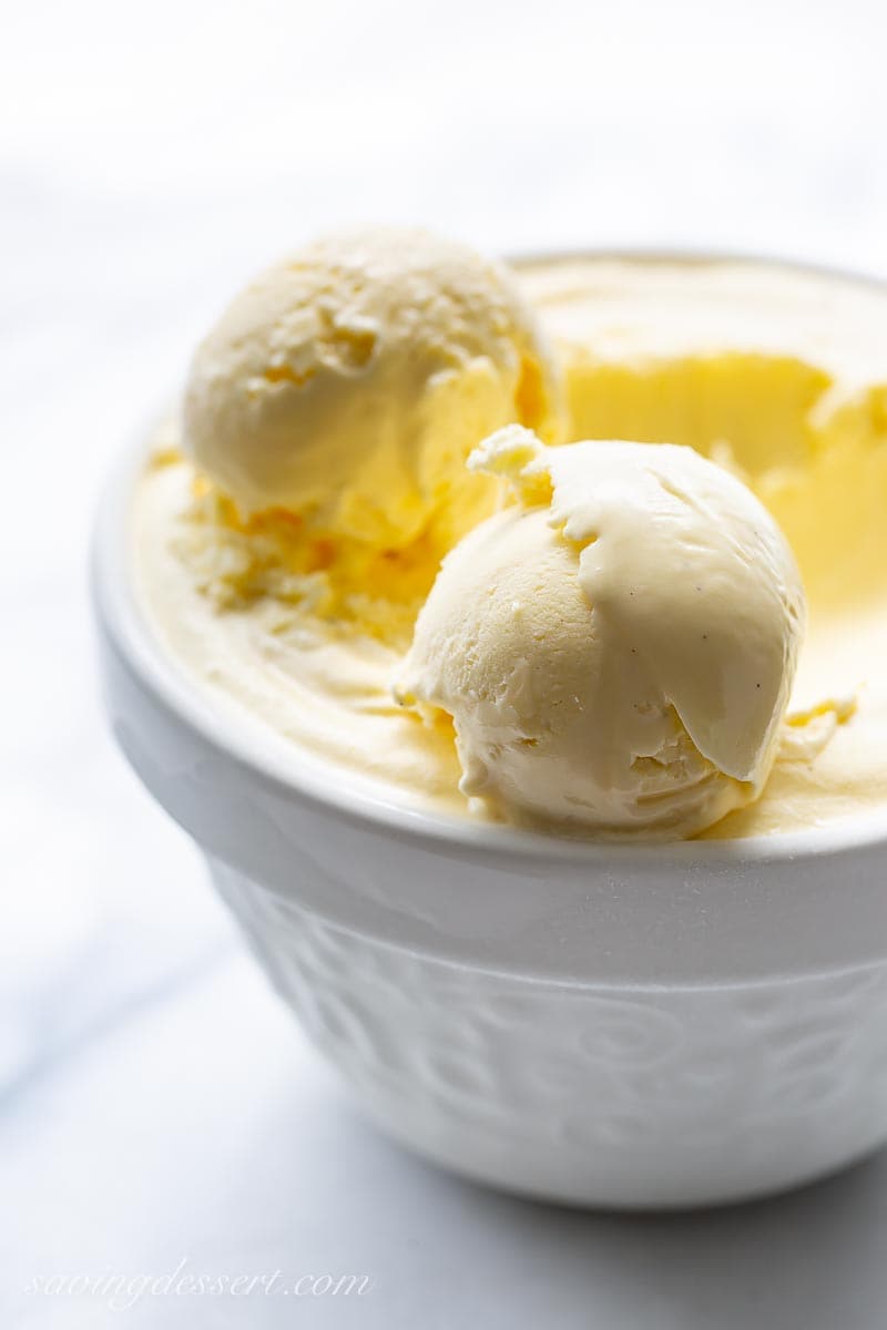 A white bowl of ice cream with two scoops set on top