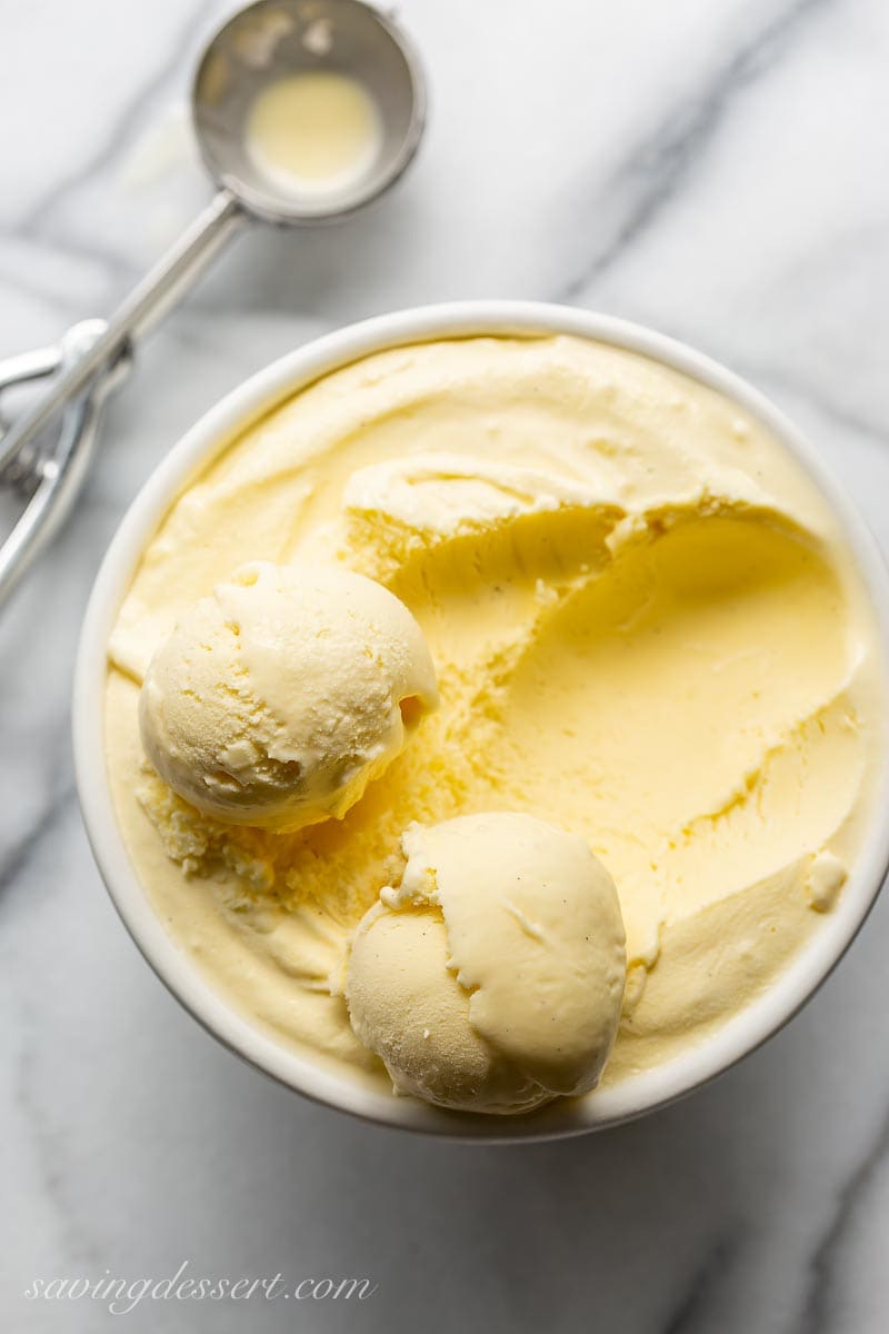 An overhead view of a bowl of ice cream with a scoop on the side