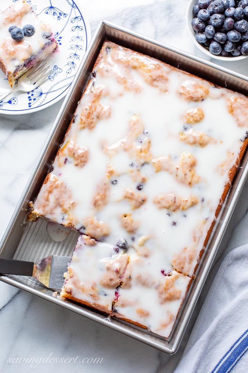 A pan with a sliced blueberry zucchini cake topped with a buttermilk glaze