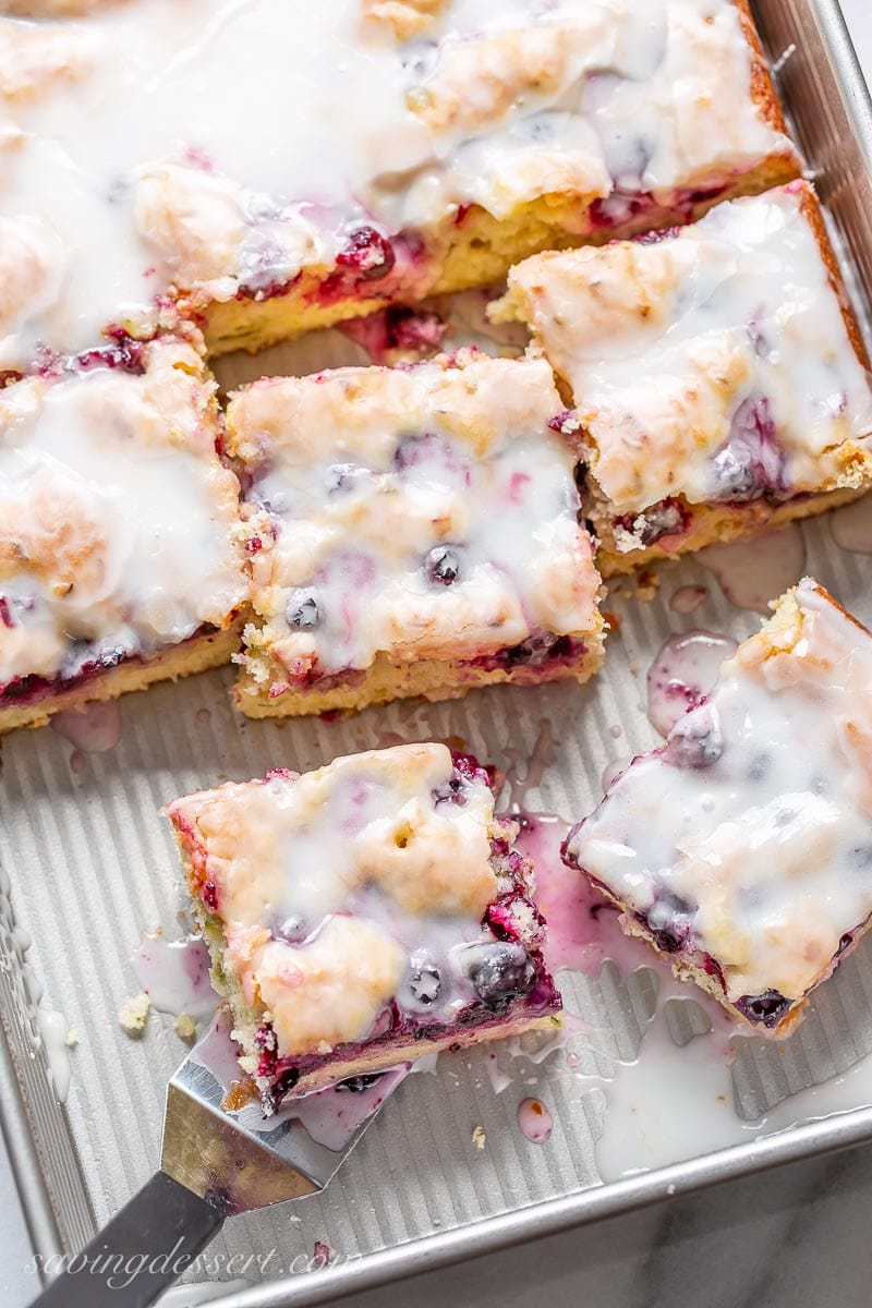 A pan with a sliced blueberry zucchini cake with a buttermilk glaze on top