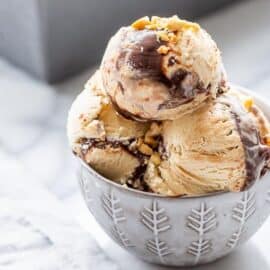 A close up of a bowl of peanut butter fudge ripple ice cream topped with chopped peanuts