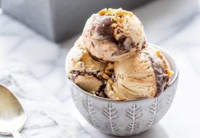 A close up of a bowl of peanut butter fudge ripple ice cream topped with chopped peanuts