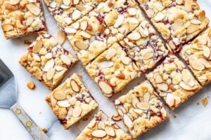 An overhead view of sliced raspberry almond bars and a spatula