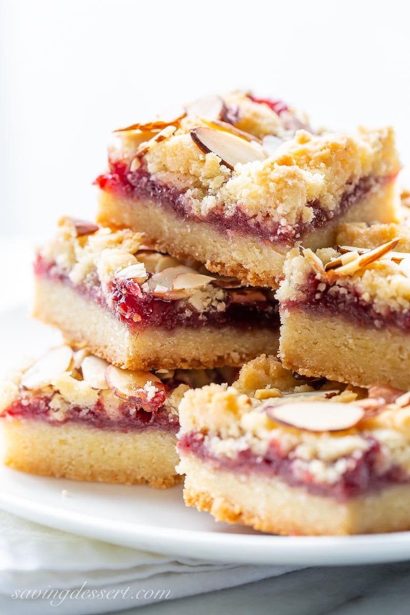 A side view of a stack of raspberry almond bars on a plate