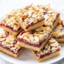 A plate of raspberry bars topped with sliced almonds