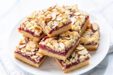 A plate of raspberry bars topped with sliced almonds