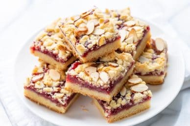 A plate of raspberry bars topped with sliced almonds