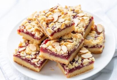 A plate of raspberry bars topped with sliced almonds