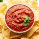A bowl of tomato salsa with chips and cilantro