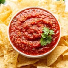 A bowl of tomato salsa with chips and cilantro