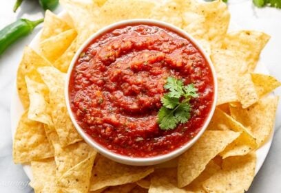 A bowl of tomato salsa with chips and cilantro
