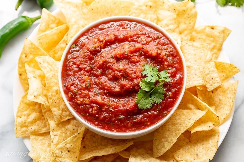 A bowl of chunky tomato salsa with chips and cilantro