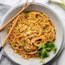 A bowl of spicy peanut noodles with chopsticks