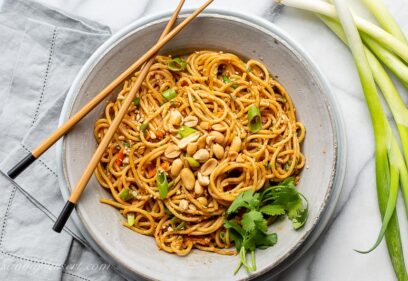 A bowl of spicy peanut noodles with chopsticks