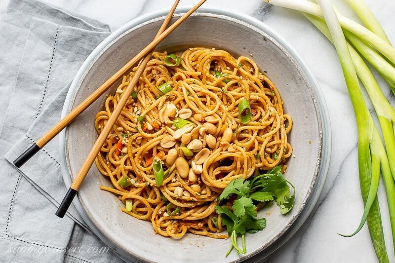 A bowl of spicy peanut noodles with chopsticks