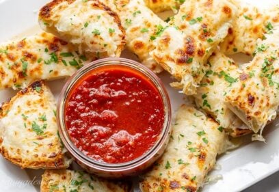 A platter of cheesy garlic bread served with marinara