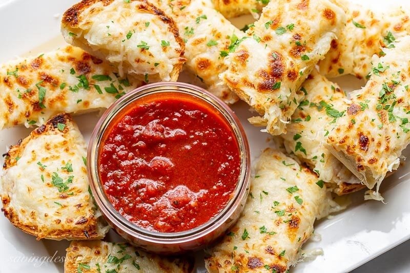 A platter of cheesy garlic bread served with marinara