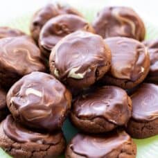 A closeup of a plate of chocolate cookies topped with a chocolate mint icing