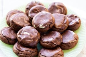 A closeup of a plate of chocolate cookies topped with a chocolate mint icing