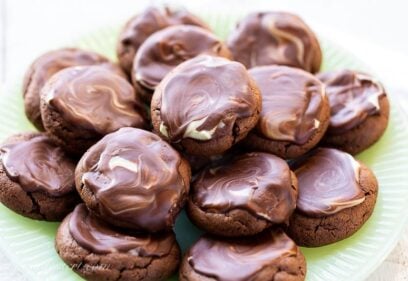 A closeup of a plate of chocolate cookies topped with a chocolate mint icing