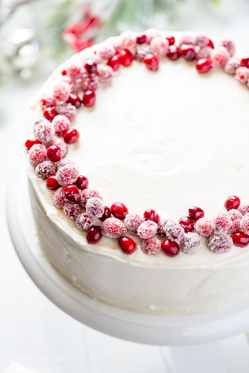 An overhead view of a white layer cake decorated with sugared cranberries