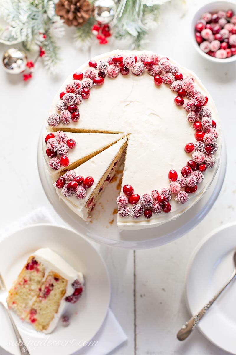 A sliced layer cake decorated with sugared cranberries