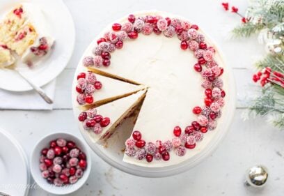 An overhead view of a sliced Cranberry Christmas Cake decorated with sugared cranberries